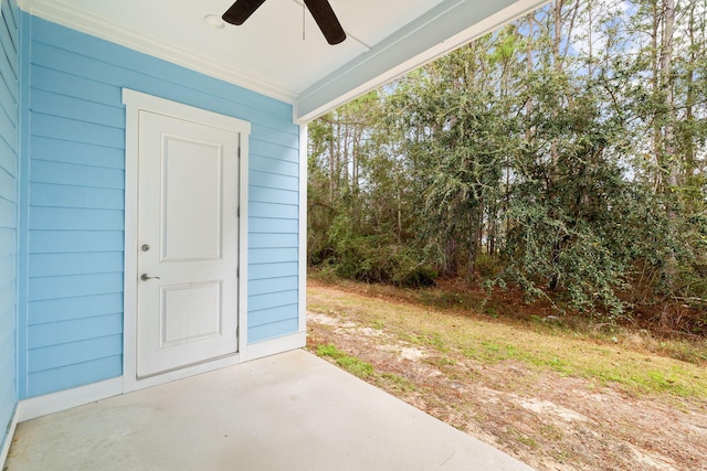 view of exterior entry with ceiling fan and a patio