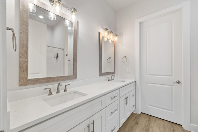 bathroom with wood finished floors, double vanity, and a shower