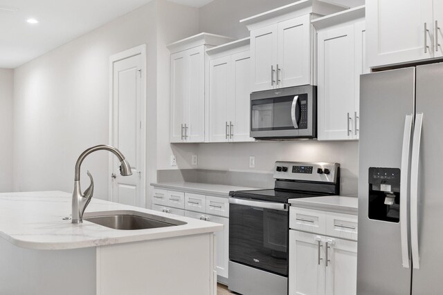 kitchen featuring stainless steel appliances, a sink, white cabinets, a center island with sink, and recessed lighting
