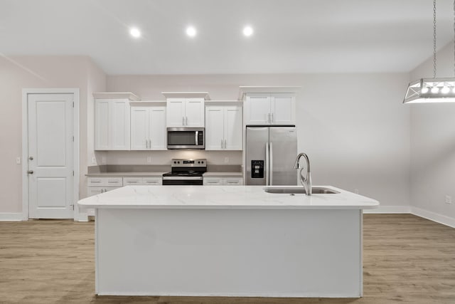 kitchen featuring stainless steel appliances, a sink, white cabinets, an island with sink, and light wood-style floors