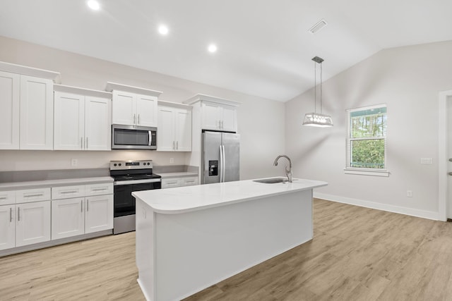 kitchen with appliances with stainless steel finishes, a sink, vaulted ceiling, white cabinets, and a kitchen island with sink