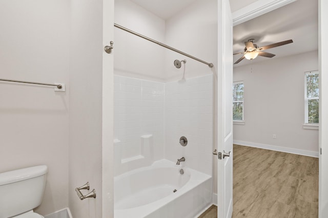 full bath with toilet, wood finished floors, ceiling fan, baseboards, and washtub / shower combination