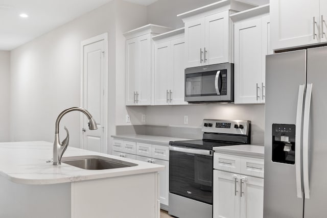 kitchen featuring stainless steel appliances, a sink, white cabinets, a center island with sink, and recessed lighting