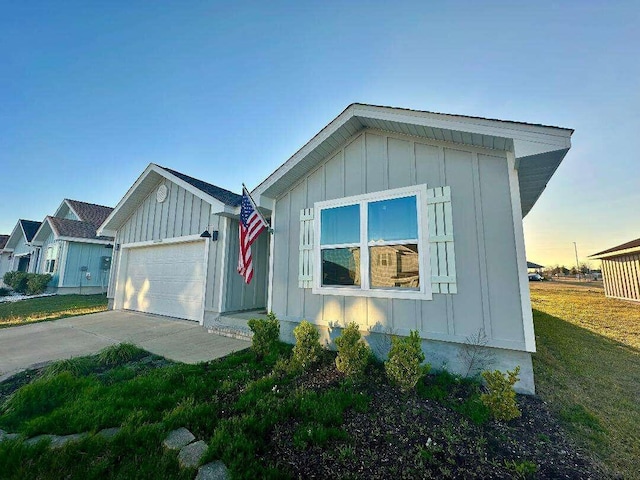 view of front of house featuring a garage, a front lawn, concrete driveway, and board and batten siding