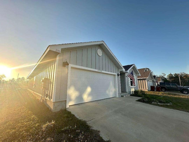 view of side of home featuring an attached garage, board and batten siding, and driveway