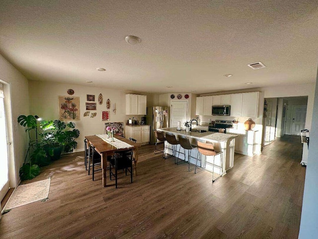 dining room featuring visible vents, dark wood-style flooring, and a textured ceiling