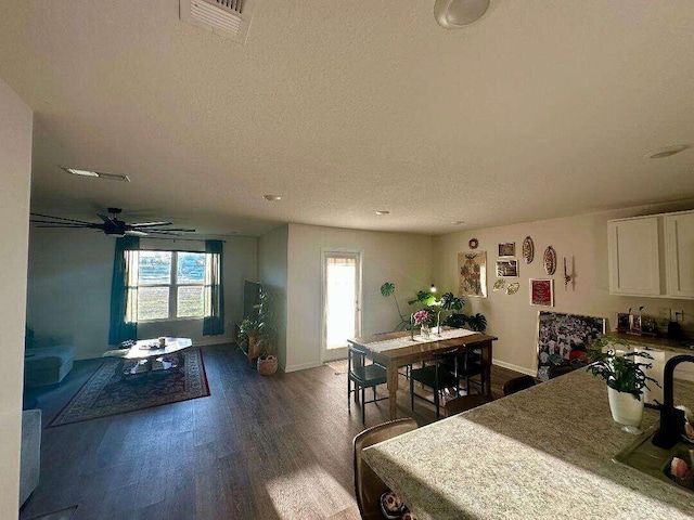 dining area featuring visible vents, dark wood-type flooring, ceiling fan, baseboards, and a textured ceiling