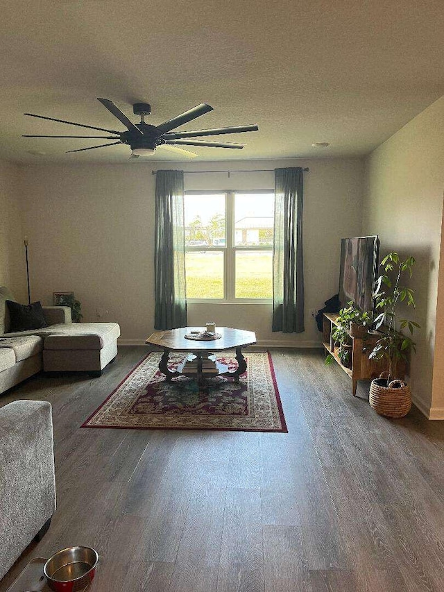 living room with baseboards, wood finished floors, and a ceiling fan