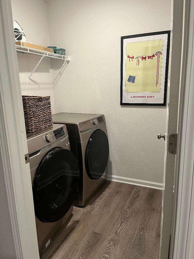 laundry area featuring laundry area, washing machine and dryer, baseboards, and wood finished floors