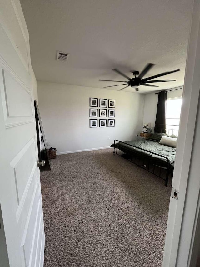 carpeted bedroom with visible vents, baseboards, and ceiling fan