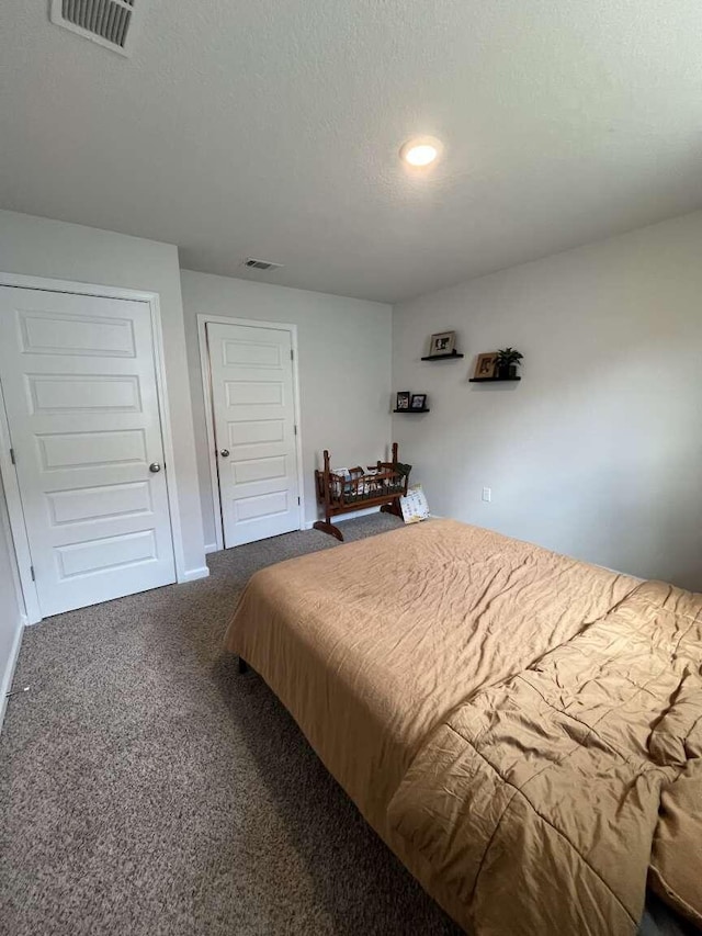 bedroom with carpet flooring, baseboards, visible vents, and a textured ceiling