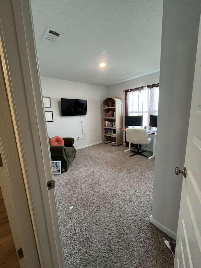 interior space with visible vents, baseboards, carpet floors, and a textured ceiling