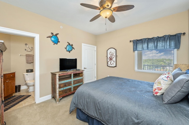 bedroom featuring light colored carpet, ensuite bath, baseboards, and ceiling fan