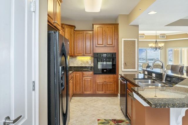 kitchen with decorative backsplash, black appliances, dark stone countertops, and a sink