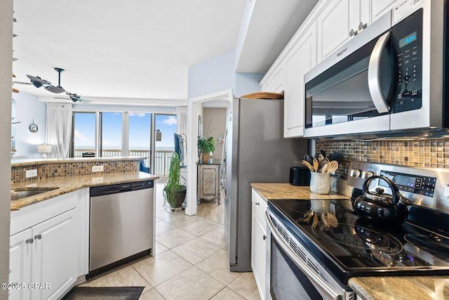 kitchen featuring stainless steel appliances, backsplash, light tile patterned flooring, and white cabinetry