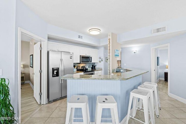 kitchen with stainless steel appliances, visible vents, and light tile patterned flooring