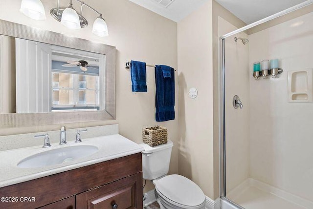 bathroom with vanity, a shower stall, toilet, and ceiling fan