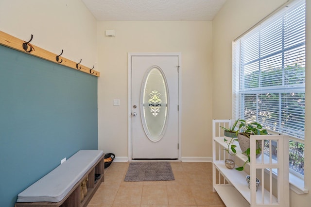 foyer with light tile patterned floors, baseboards, and a textured ceiling