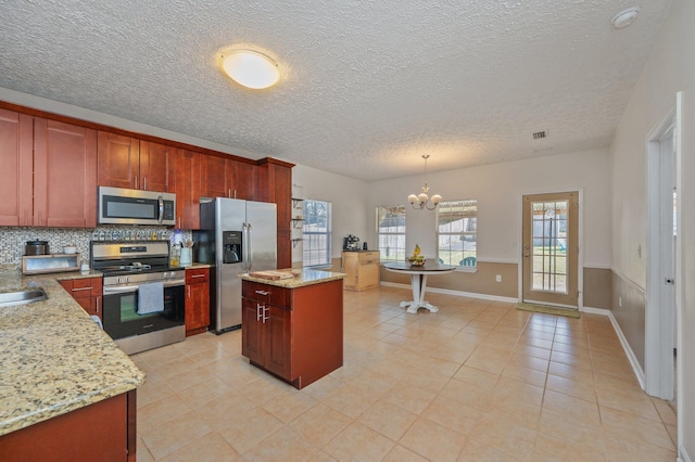 kitchen with backsplash, a kitchen island, a chandelier, pendant lighting, and stainless steel appliances