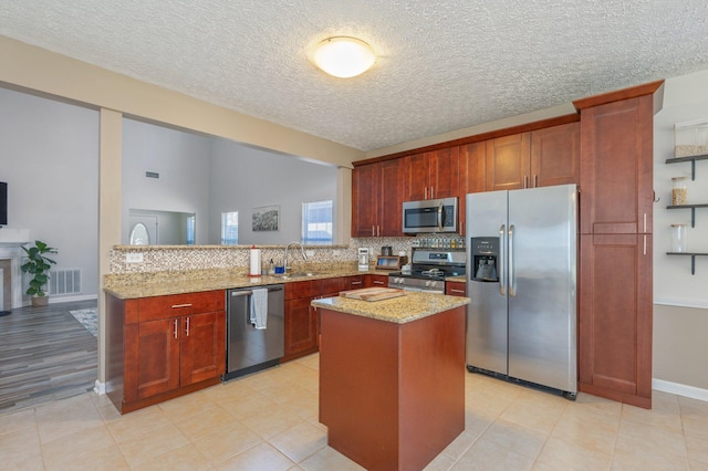 kitchen with visible vents, backsplash, appliances with stainless steel finishes, a peninsula, and light stone countertops