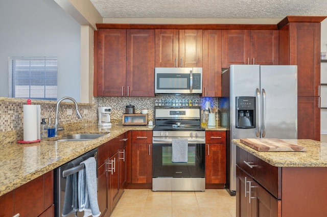 kitchen with reddish brown cabinets, tasteful backsplash, appliances with stainless steel finishes, and a sink