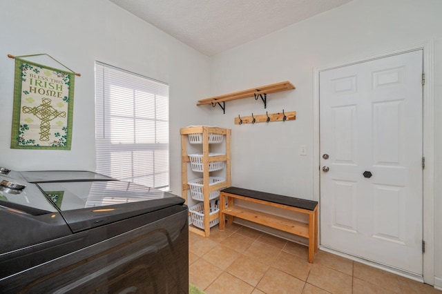 mudroom featuring light tile patterned floors, independent washer and dryer, and a textured ceiling