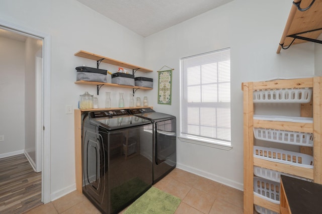 laundry room with washer and clothes dryer, a textured ceiling, light tile patterned flooring, baseboards, and laundry area