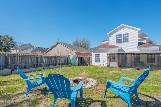 view of yard with a sunroom, a fenced backyard, and an outdoor fire pit