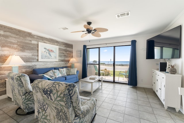 living area featuring visible vents, wooden walls, ceiling fan, and an accent wall