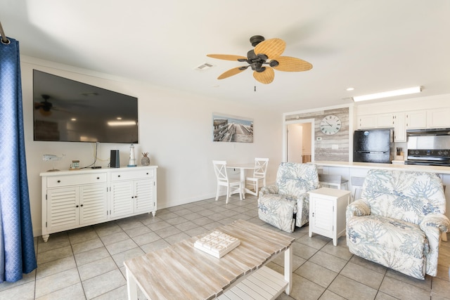 living room featuring light tile patterned floors, visible vents, baseboards, and a ceiling fan