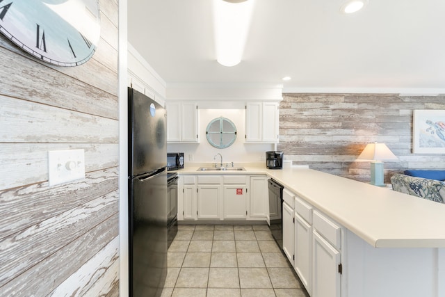 kitchen featuring black appliances, a sink, a peninsula, wood walls, and white cabinets