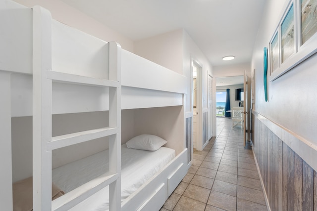 hall featuring light tile patterned flooring and wainscoting