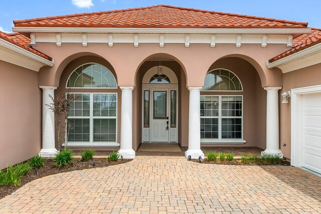 114 Golf Dr, Panama City Beach, FL 32408 - entrance to property featuring stucco siding, a tiled roof, decorative driveway, and covered porch