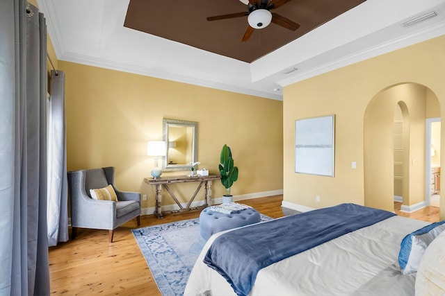 114 Golf Dr, Panama City Beach, FL 32408 - bedroom featuring arched walkways, a tray ceiling, light wood-type flooring, crown molding, and baseboards
