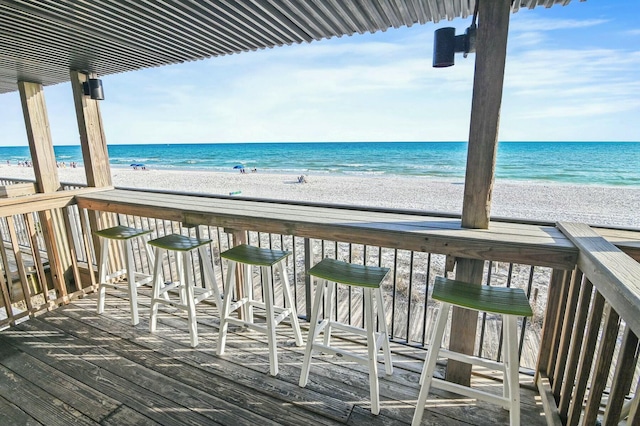 wooden deck featuring a beach view and a water view