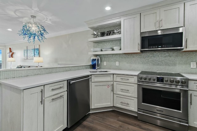 kitchen with a peninsula, a sink, stainless steel appliances, light countertops, and crown molding