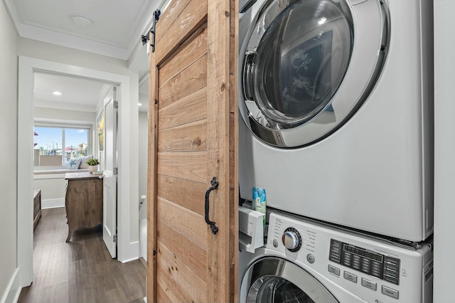 laundry area with dark wood-type flooring, ornamental molding, stacked washer / drying machine, baseboards, and laundry area