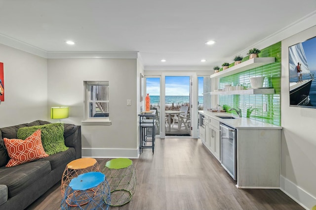 kitchen with a sink, open shelves, stainless steel dishwasher, wood finished floors, and light countertops