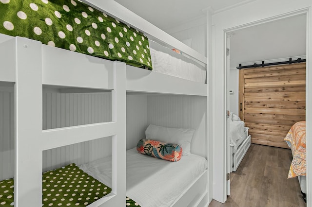 bedroom with a barn door and wood finished floors