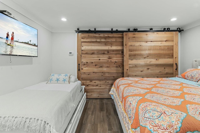 bedroom with recessed lighting, dark wood-type flooring, and a barn door