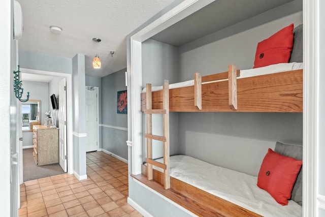 bedroom with baseboards, a textured ceiling, and tile patterned flooring