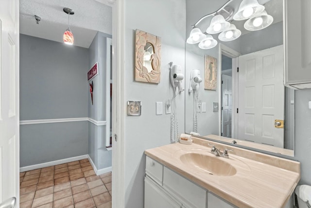 bathroom with vanity, tile patterned floors, baseboards, and a textured ceiling