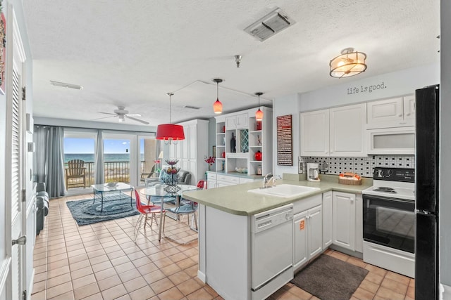 kitchen with a sink, visible vents, white appliances, and white cabinets