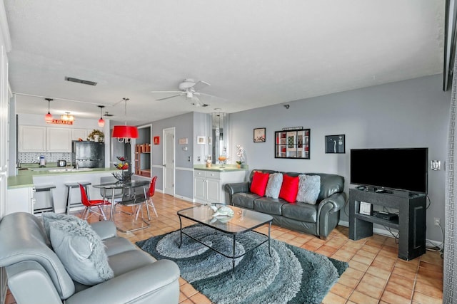 living area with light tile patterned floors, visible vents, baseboards, and a ceiling fan