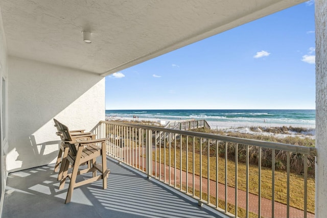 balcony featuring a view of the beach and a water view