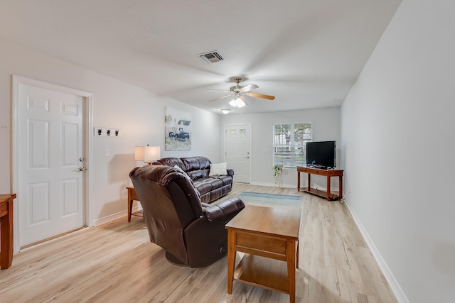 living area featuring visible vents, baseboards, ceiling fan, and light wood finished floors