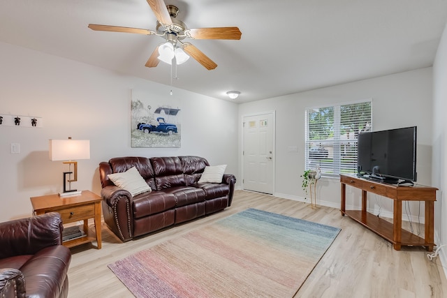 living area with light wood-style floors, baseboards, and ceiling fan