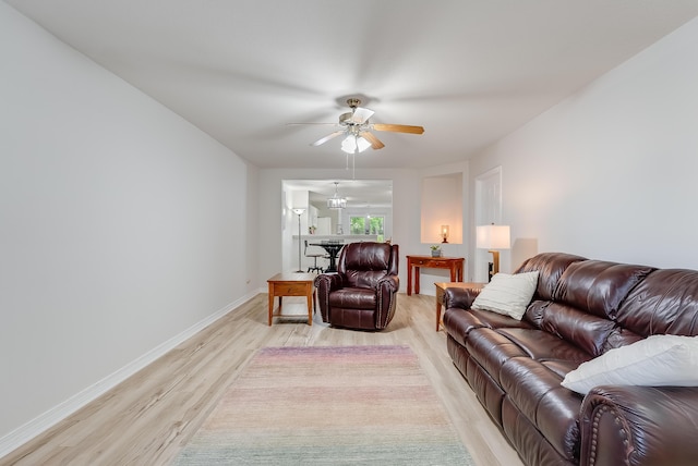 living area featuring a ceiling fan, light wood-type flooring, and baseboards