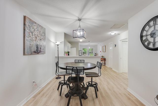 dining space featuring light wood finished floors, visible vents, and baseboards