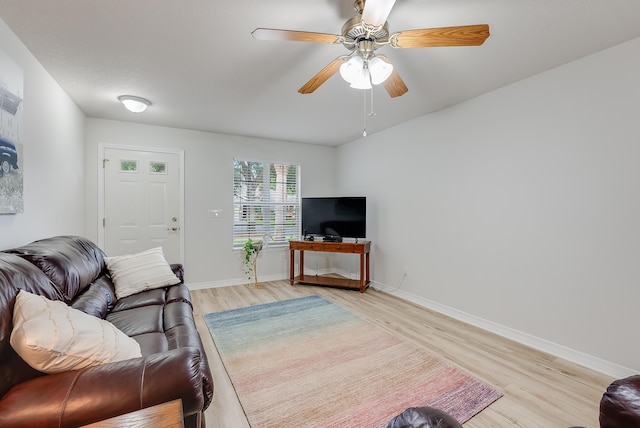 living room with a ceiling fan, baseboards, and light wood finished floors